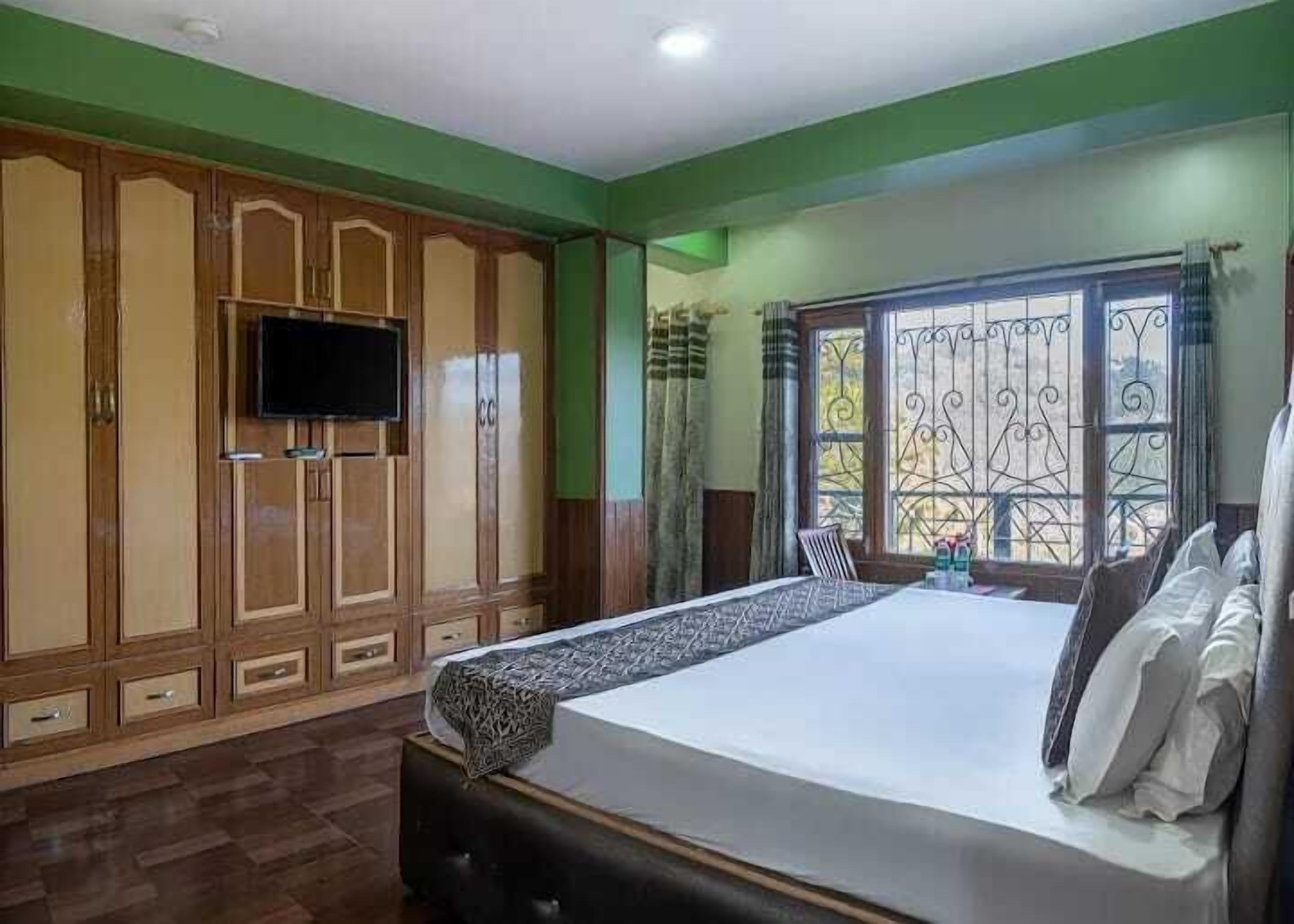 Un dormitorio con cama, armario de madera, televisor y ventana con rejas decorativas.