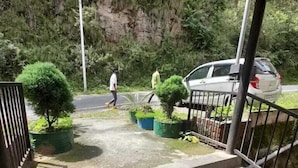 A paved pathway leading to a gated entrance with potted plants. - Oak View shimla (Shimla)