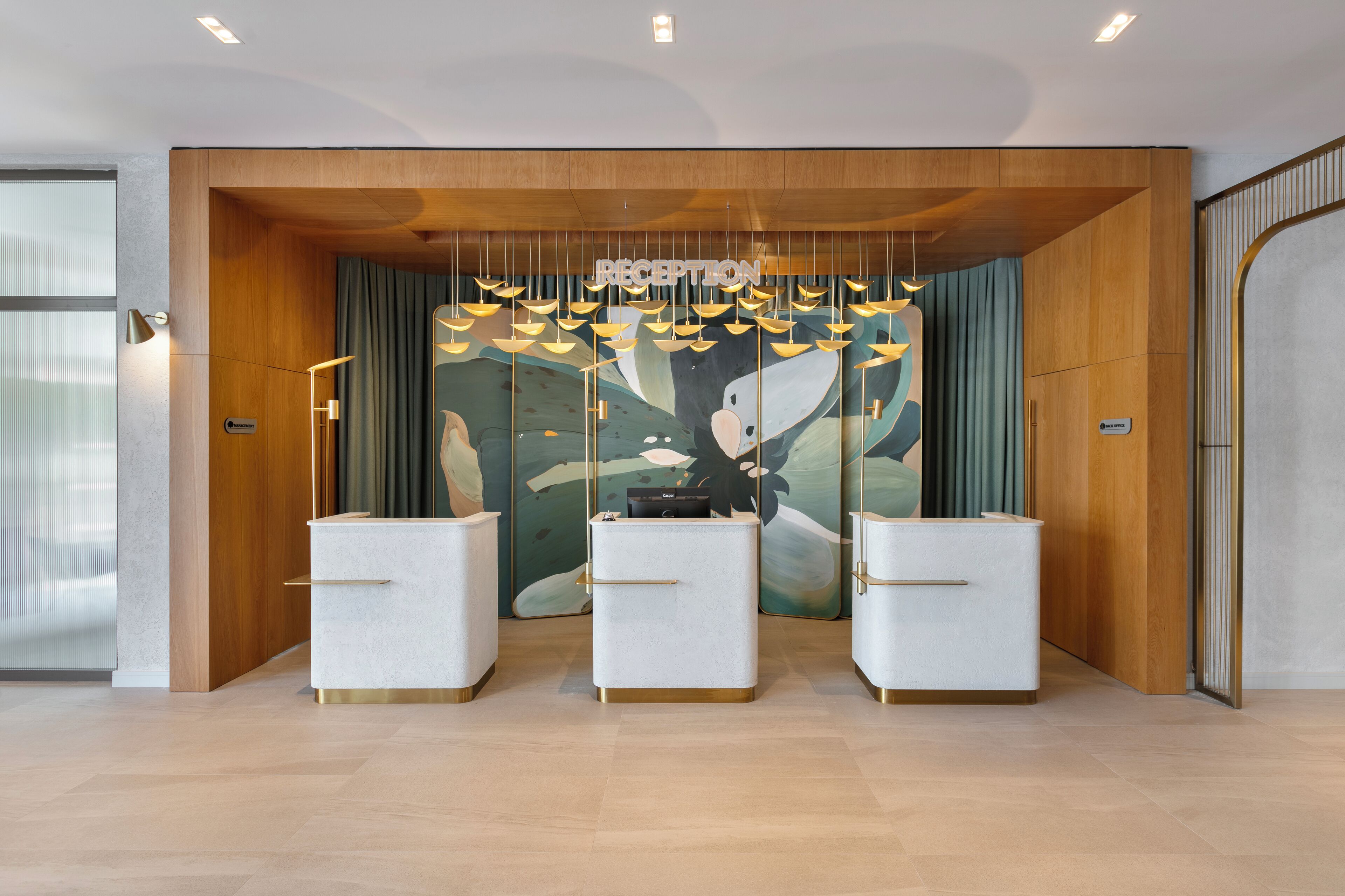 A reception area with a wooden reception desk, a wall mural, and hanging pendant lights.