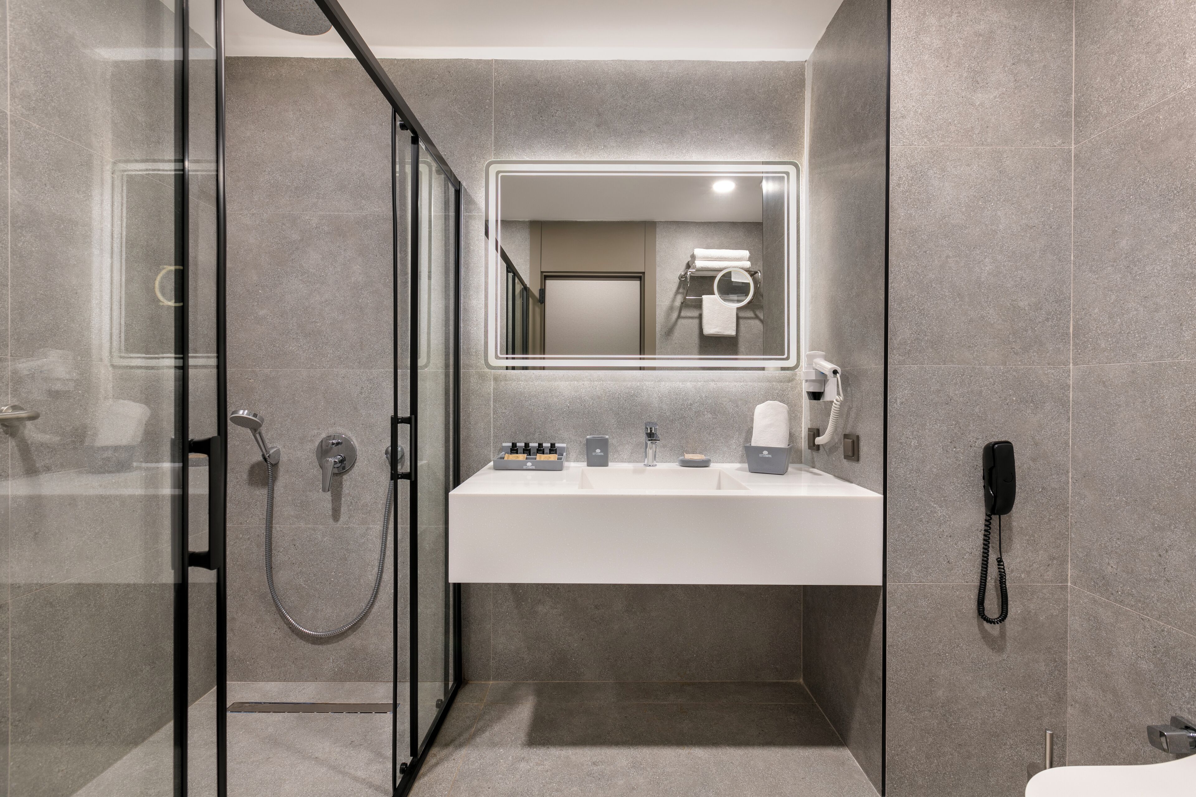 A modern bathroom with a glass shower enclosure, a white sink, and a mirror.