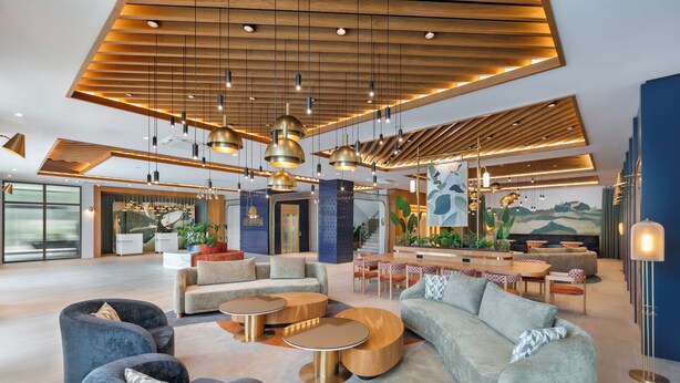 A spacious lobby with modern furniture, a bar area, and a large mural. - Keptur Hotel (Dosemealti)