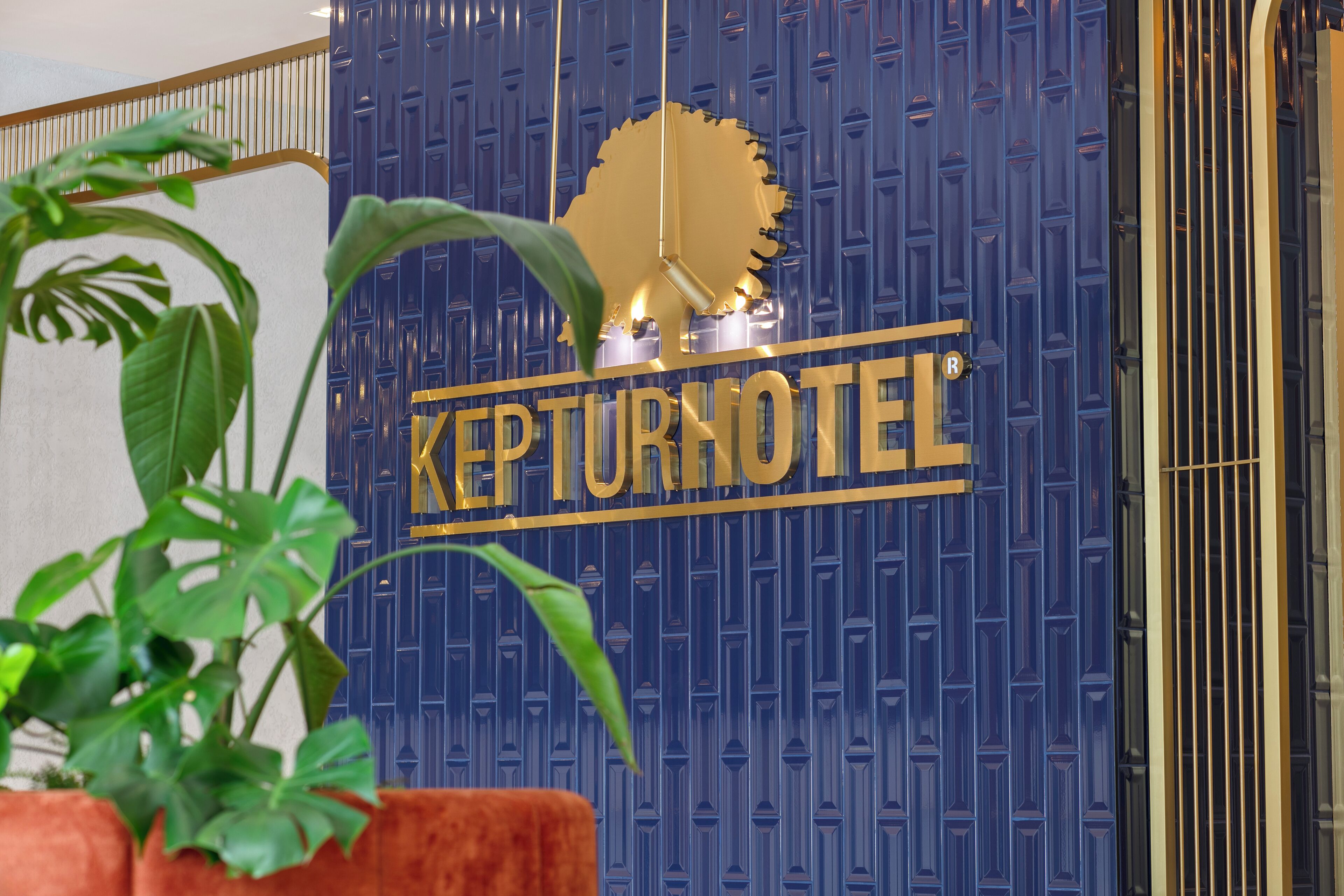 A KEPTURNOTEL sign with a large golden gear and a plant in the foreground.