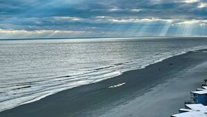 A beach with a long stretch of sand and a building with a blue roof.