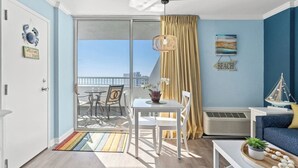 A modern living room with a balcony, a dining area, and a seating area.