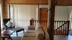A room with a sofa, a chair, a table, and a wooden staircase. - Woodstock 3 Francis St, Port Elliot (Port Elliot)