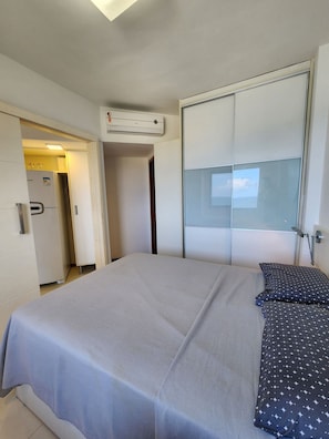 A hotel room with a bed, a wardrobe, and an air conditioning unit. - Sol Nascente (Salvador)