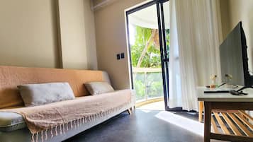 Una habitación moderna con sofá, escritorio y vistas a zonas verdes.