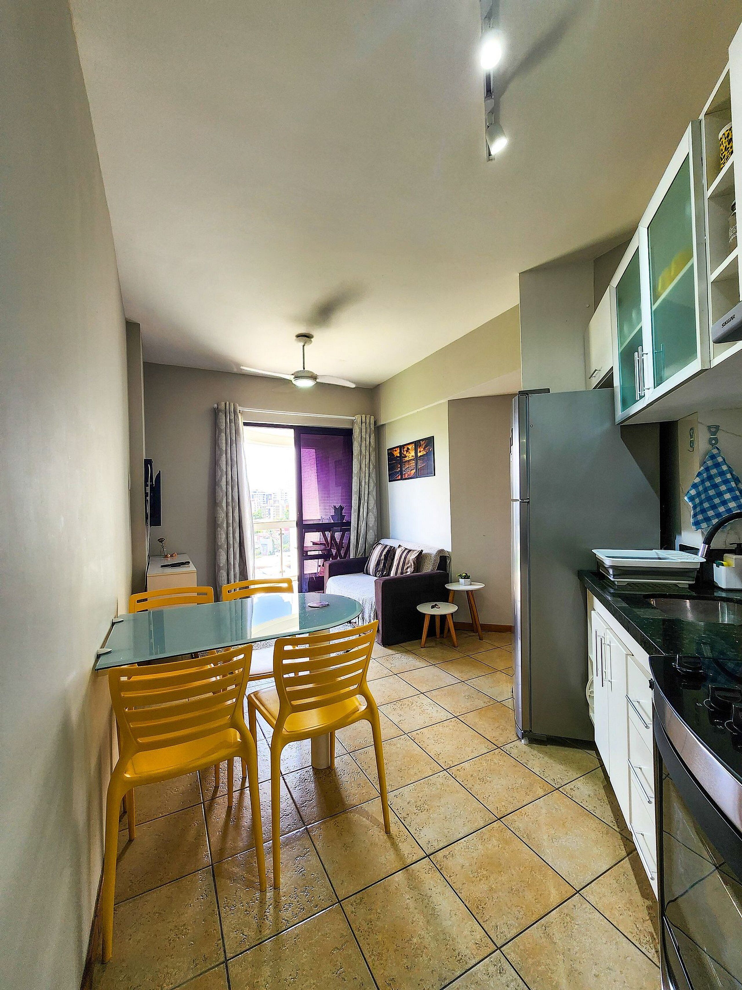 A compact kitchen with a dining area, a refrigerator, and a ceiling fan.