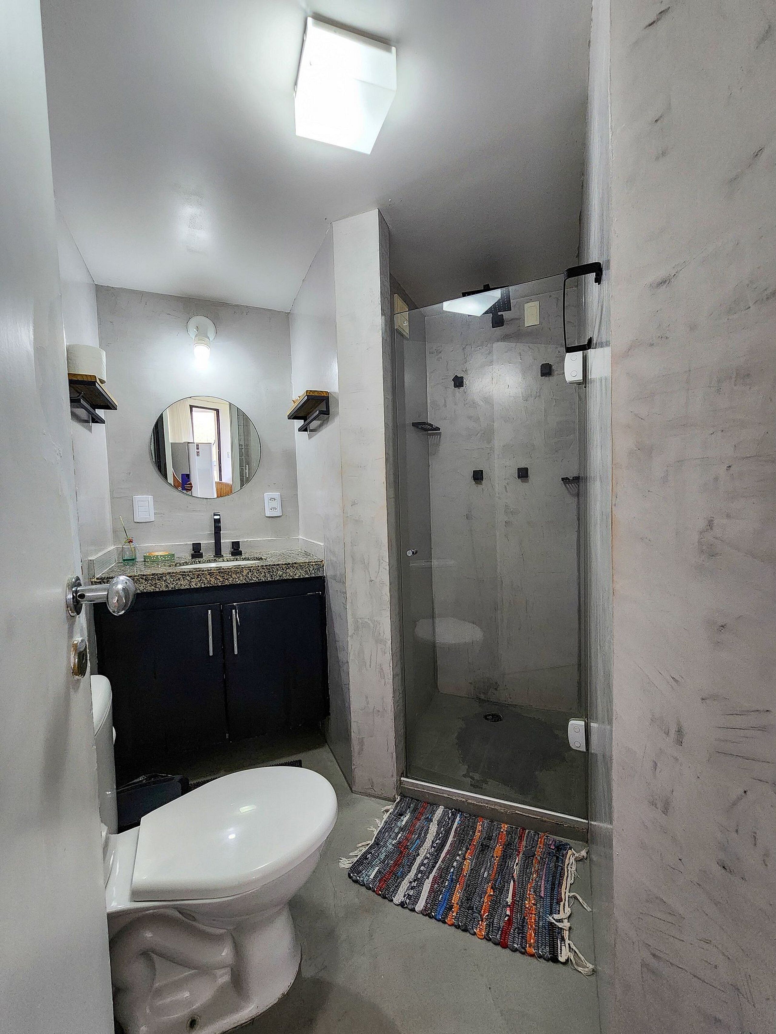 A bathroom with a toilet, sink, mirror, and shower.