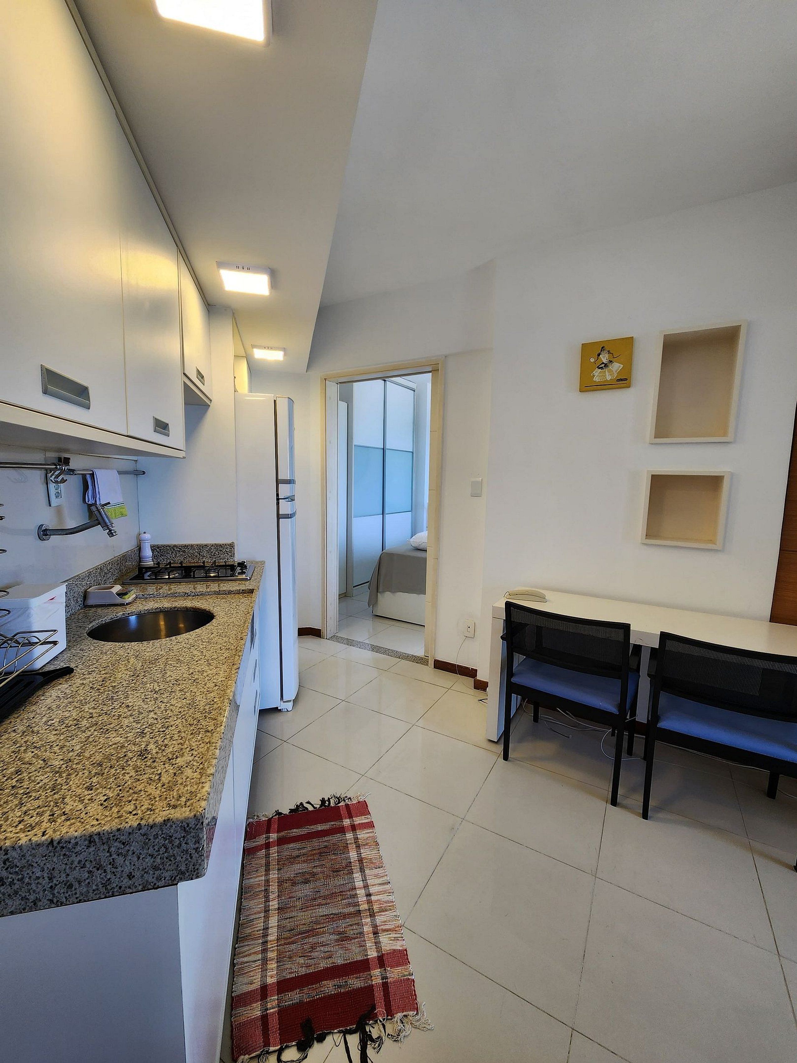 A modern kitchen with granite countertops, a built-in oven, and a dining area with a bench and table.