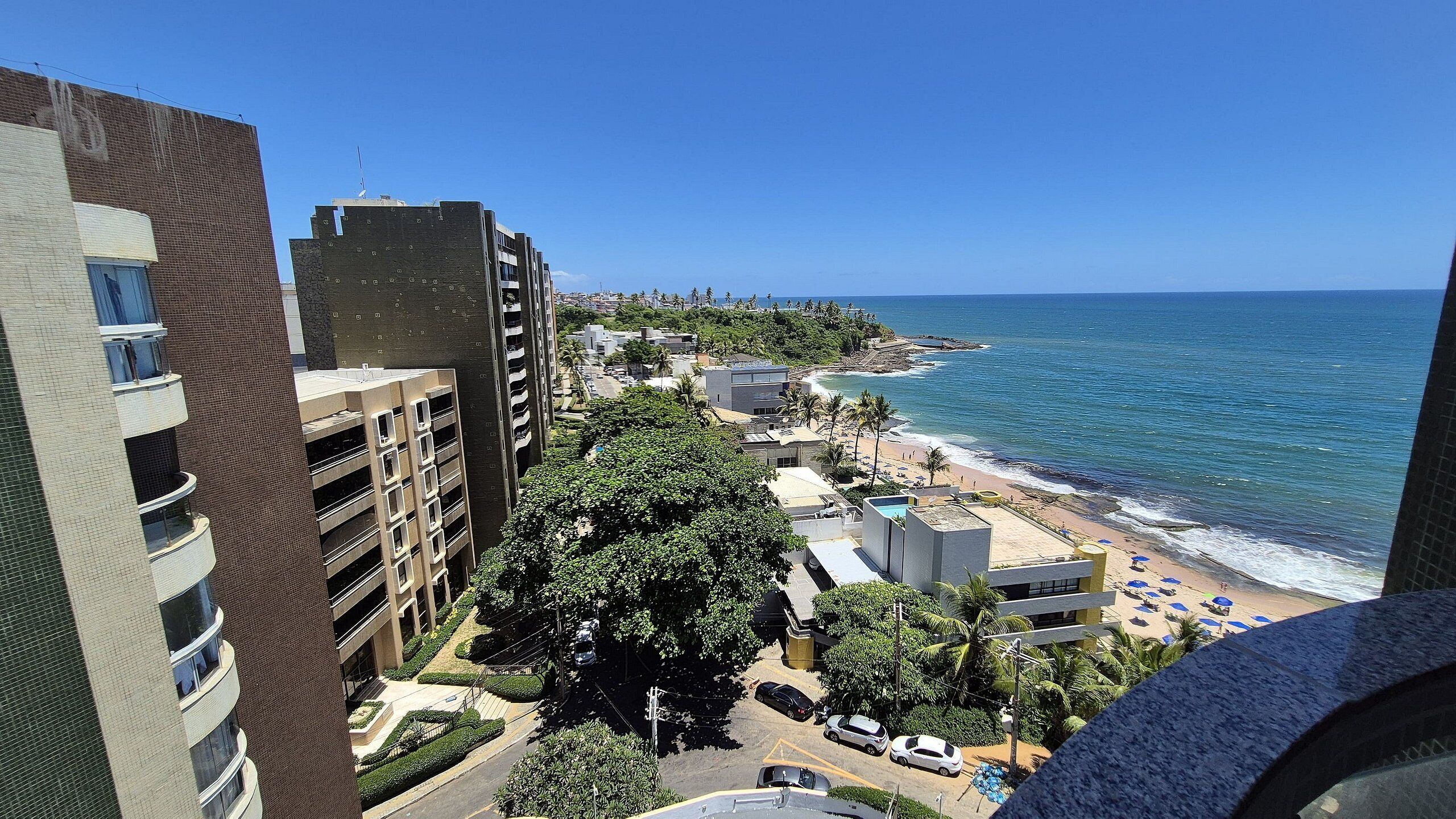 A high-rise building with multiple balconies overlooking a beach and ocean.