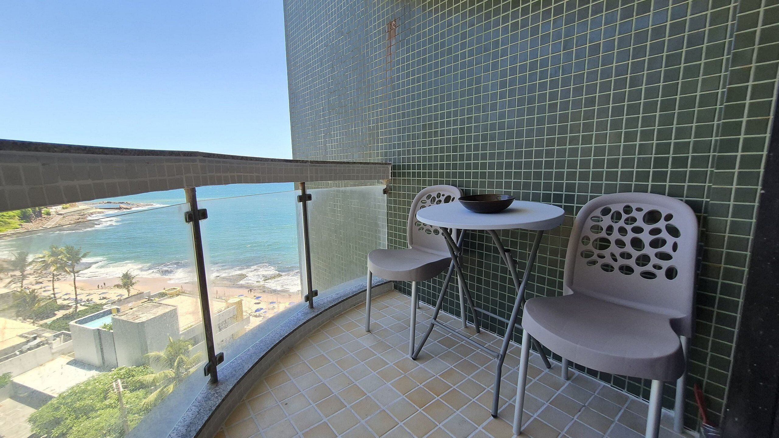 Een balkon met uitzicht op het strand en de oceaan, een klein rond tafeltje en twee stoelen.