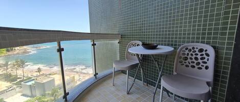 Een balkon met uitzicht op het strand en de oceaan, een klein rond tafeltje en twee stoelen.