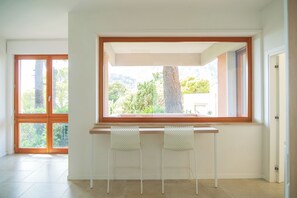 A room with a large window, two white chairs, and a wooden table. - Capri Koral Guest House (Capri)