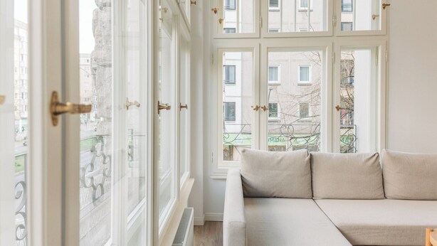 Et værelse med et stort vindue, en sofa og udsigt til bygninger.