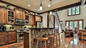A spacious kitchen with wooden cabinets, a stone island, and bar stools. - Elk Horn - Big Canoe GA (Big Canoe)