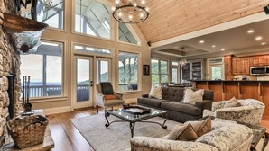 A spacious living room with a fireplace, large windows, and a view of the outdoors. - Endless Sky Lodge - Big Canoe GA (Big Canoe)