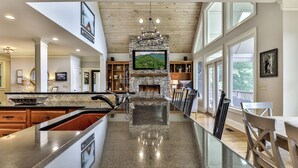 A spacious kitchen with a stone fireplace, modern appliances, and a large island. - Endless Sky Lodge - Big Canoe GA (Big Canoe)