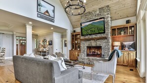 A spacious living room with a stone fireplace, a large flat-screen TV, and a cozy seating area. - Endless Sky Lodge - Big Canoe GA (Big Canoe)