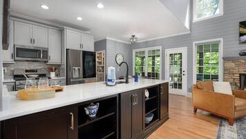 A modern kitchen with white cabinets, stainless steel appliances, and a large island.