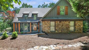 A two-story house with a stone facade, a front porch, and a garage.