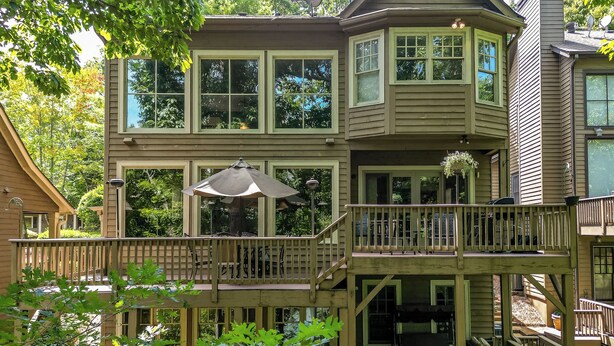 Een huis met twee verdiepingen, een balkon en een overdekte patio.