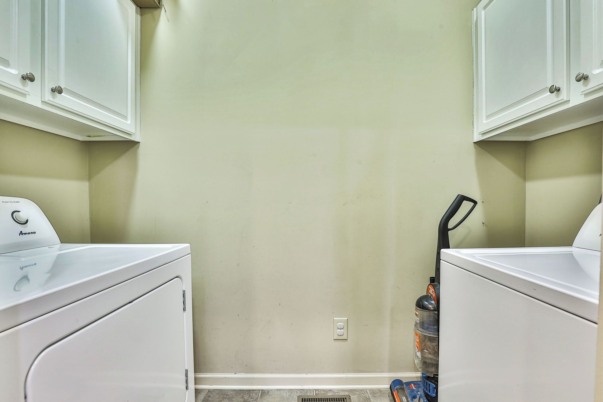 A laundry room with two white washing machines, a water heater, and a water filter.