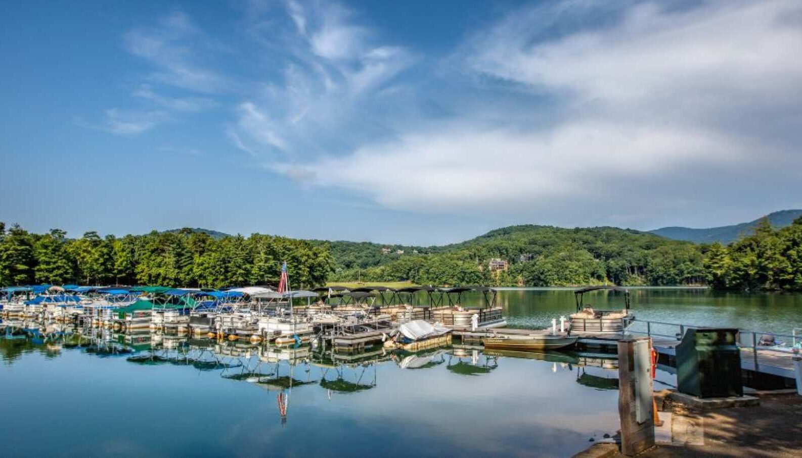 A marina with boats docked, surrounded by forested hills.