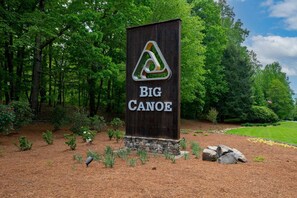 A wooden sign with 'BIG CANOE' written on it, surrounded by a landscaped area with trees and shrubs. - Mountain Time - Big Canoe GA (Big Canoe)