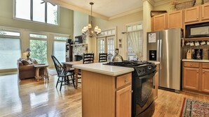 A spacious kitchen with a large island, wooden cabinets, a stainless steel refrigerator, and a dining area with a sofa and chairs. - Paradise View - Big Canoe GA (Big Canoe)