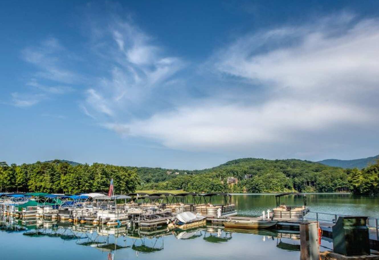 A marina with boats docked, surrounded by forested hills.
