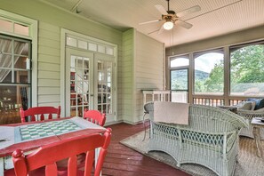 Une véranda avec une table et des chaises en bois, un canapé en osier et une vue sur l’extérieur.