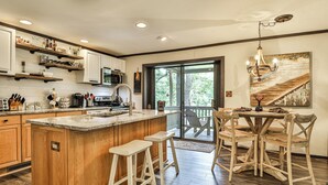 Une cuisine avec un îlot central en bois, des tabourets de bar et une table à manger avec des chaises.
