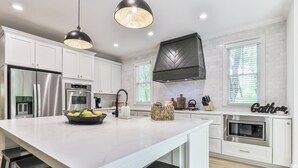 A modern kitchen with white cabinetry, stainless steel appliances, and a marble island.