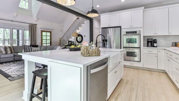 A modern kitchen with white cabinets, stainless steel appliances, and a large island.