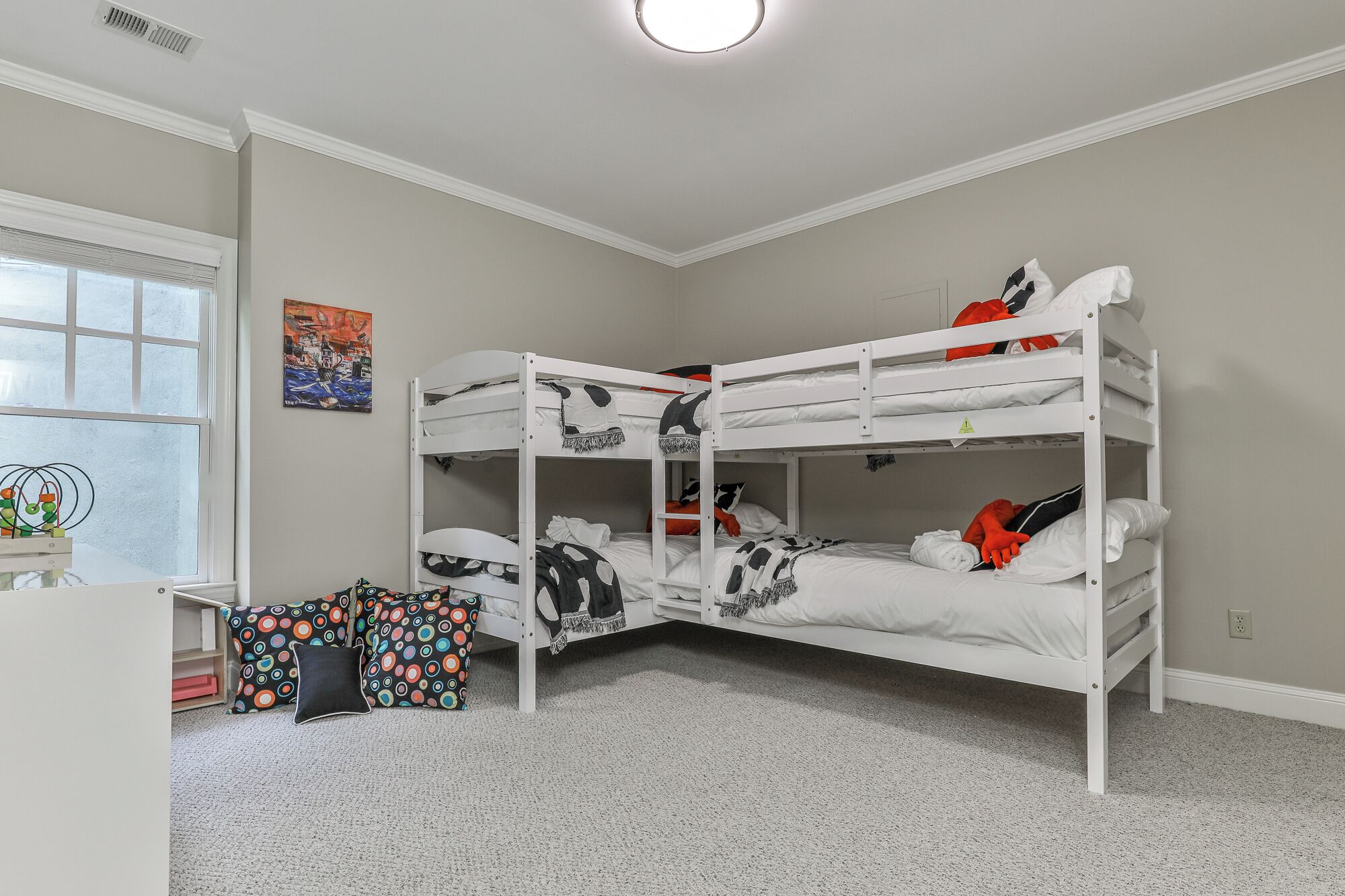 A bunk bed room with a window, a desk, and a colorful chair.