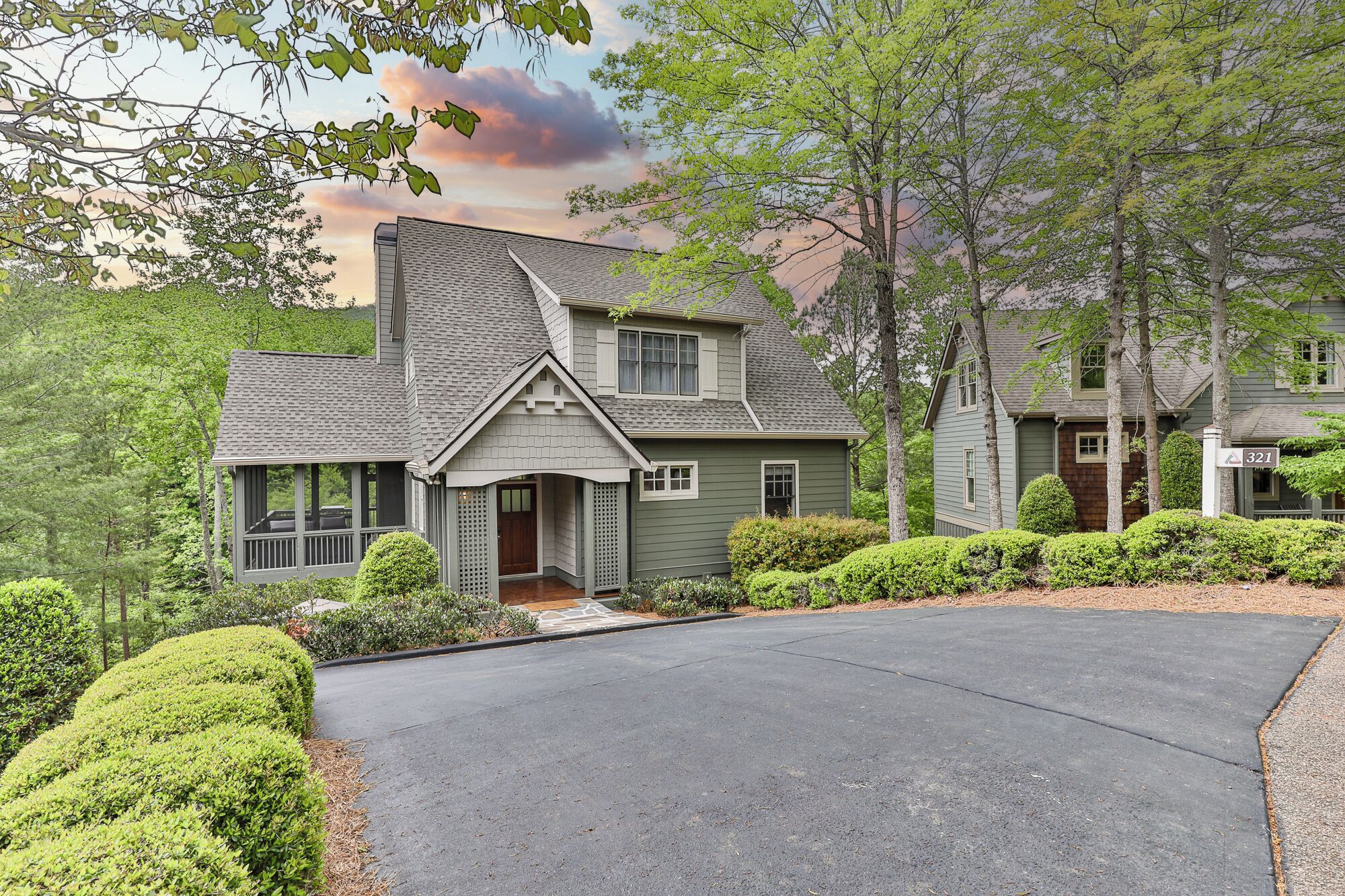 A two-story house with a steeply pitched roof, a front porch, and a driveway leading to the entrance.