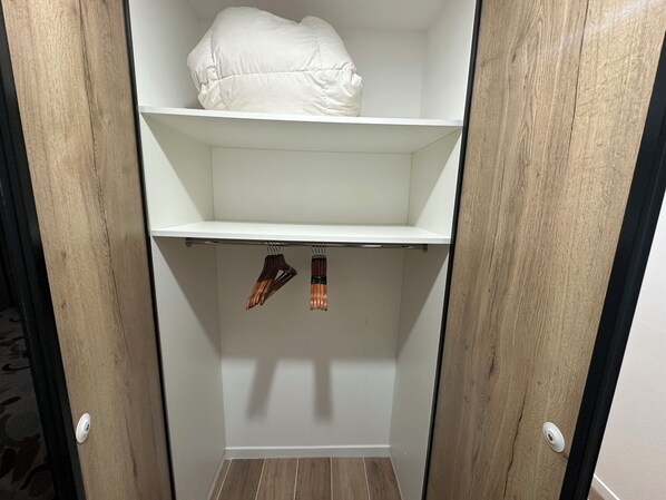 A closet with wooden doors, a white shelf, and a hanging rack with shoes. - Exceptional villa in Aix-en-Provence -Private pool • 6 people - Ideal location (Aix-en-Provence)