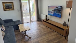 Un salon comprenant un canapé, une table basse, un téléviseur et un meuble TV en bois.