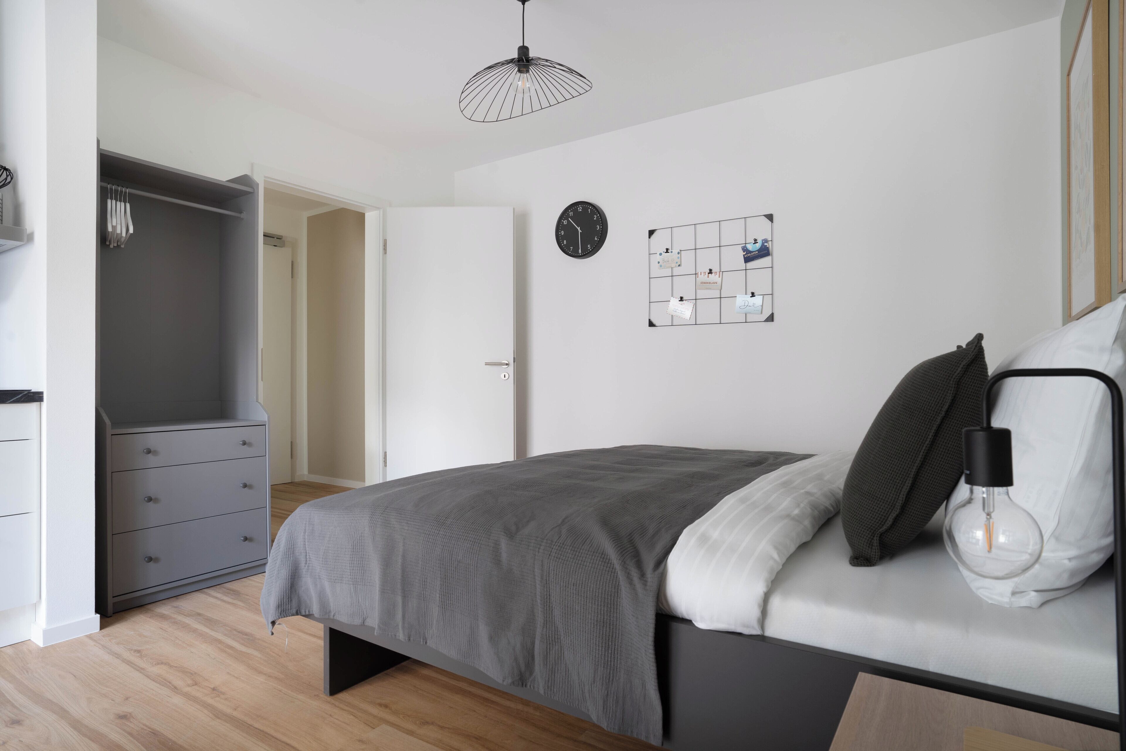 Une chambre à coucher moderne avec un lit, une lampe de chevet et une armoire.