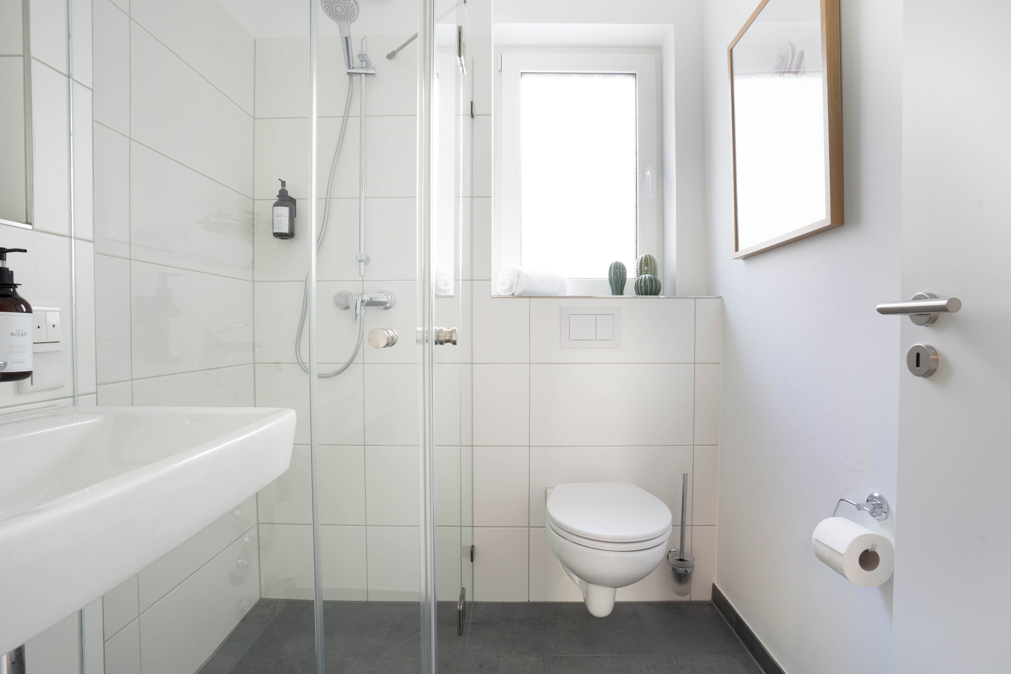 A modern bathroom with a glass-enclosed shower, a white toilet, and a sink.