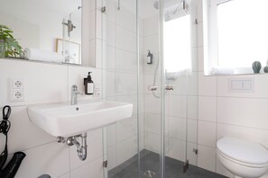 Features a sleek sink, glass-enclosed shower, and toilet.
