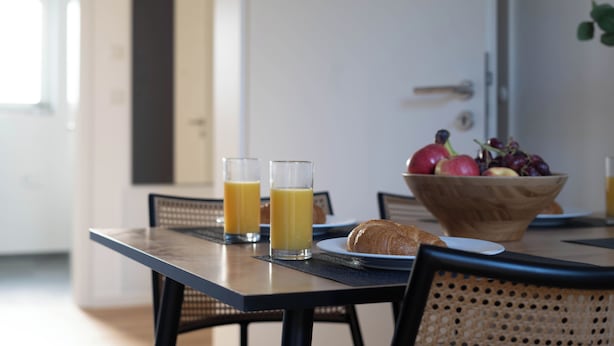 A breakfast table with two glasses of orange juice, a croissant, and a bowl of fruit. - Schöne Apartments in der Innenstadt (Osnabrueck)