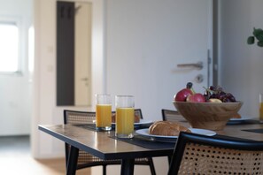Una mesa de desayuno con dos vasos de jugo de naranja, un croissant y un bol de fruta.