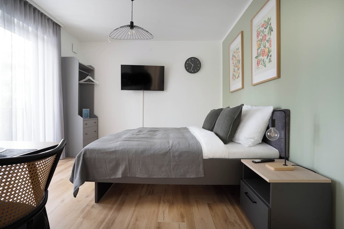 Un dormitorio moderno con una cama, una mesita de noche y un televisor montado en la pared.