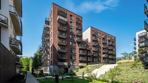 A multi-story residential building with balconies, a landscaped garden, and a clear blue sky. - Apartamenty Sun & Snow Atal City Square (Wroclaw)