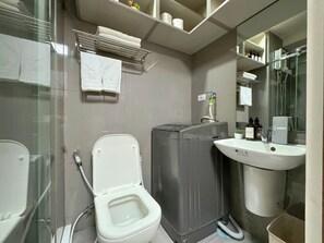 Un bany modern amb vàter, rentamànegues, un lavabo i una dutxera amb mampara de vidre.