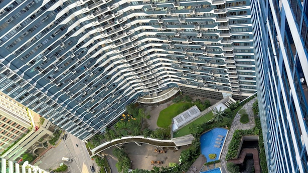 A high-rise building with a rooftop pool surrounded by greenery and a winding pathway. - 1BR Makati, Air Residences M005 (Makati)