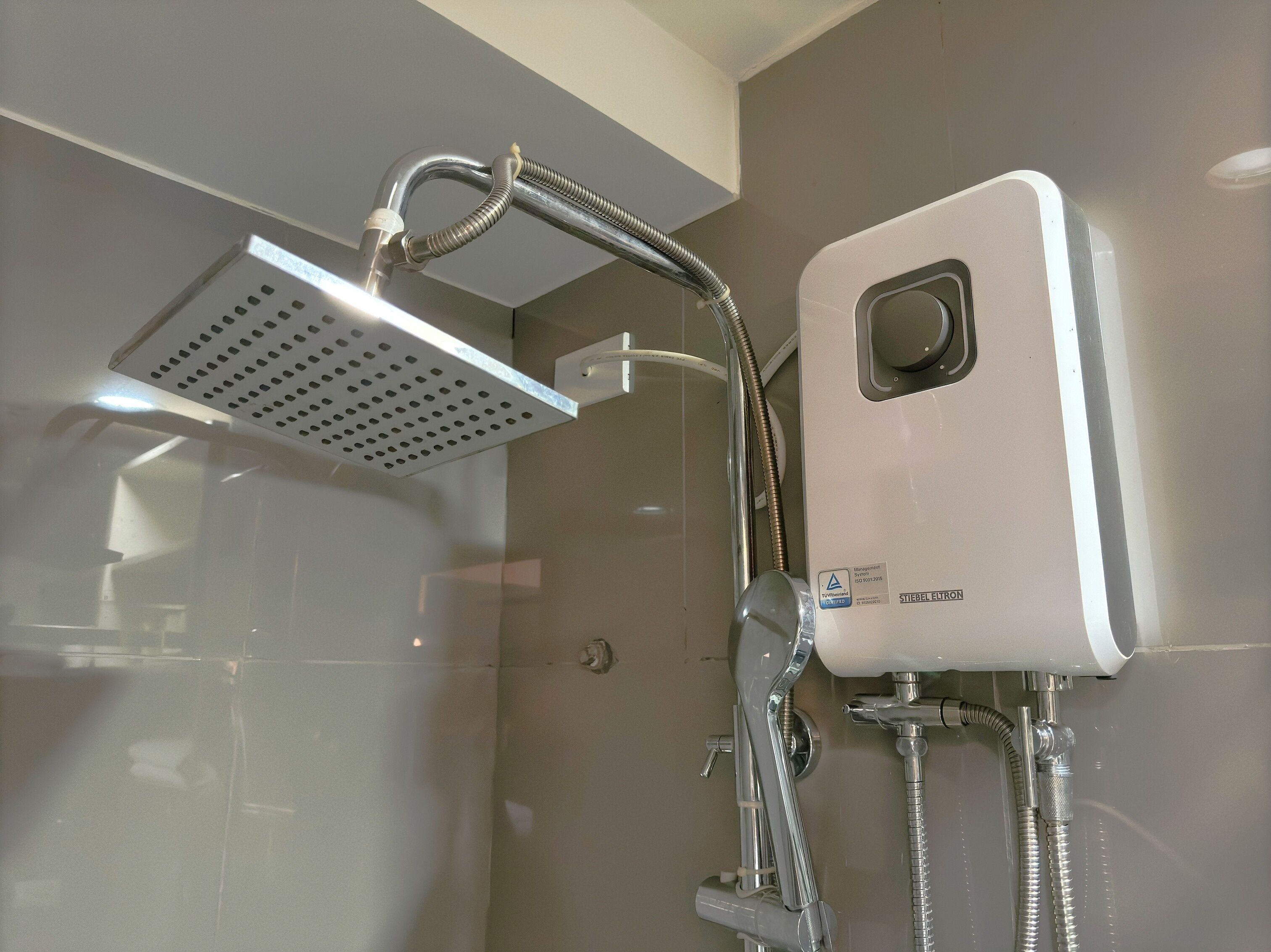 Eine moderne Dusche mit einer eckigen Duschbrause und einem Handbrausehalter.