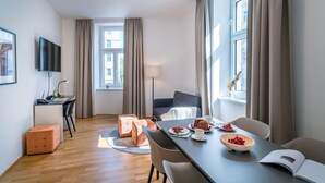Een moderne hotelkamer met een zithoek, een bank en een aan de muur bevestigde televisie.